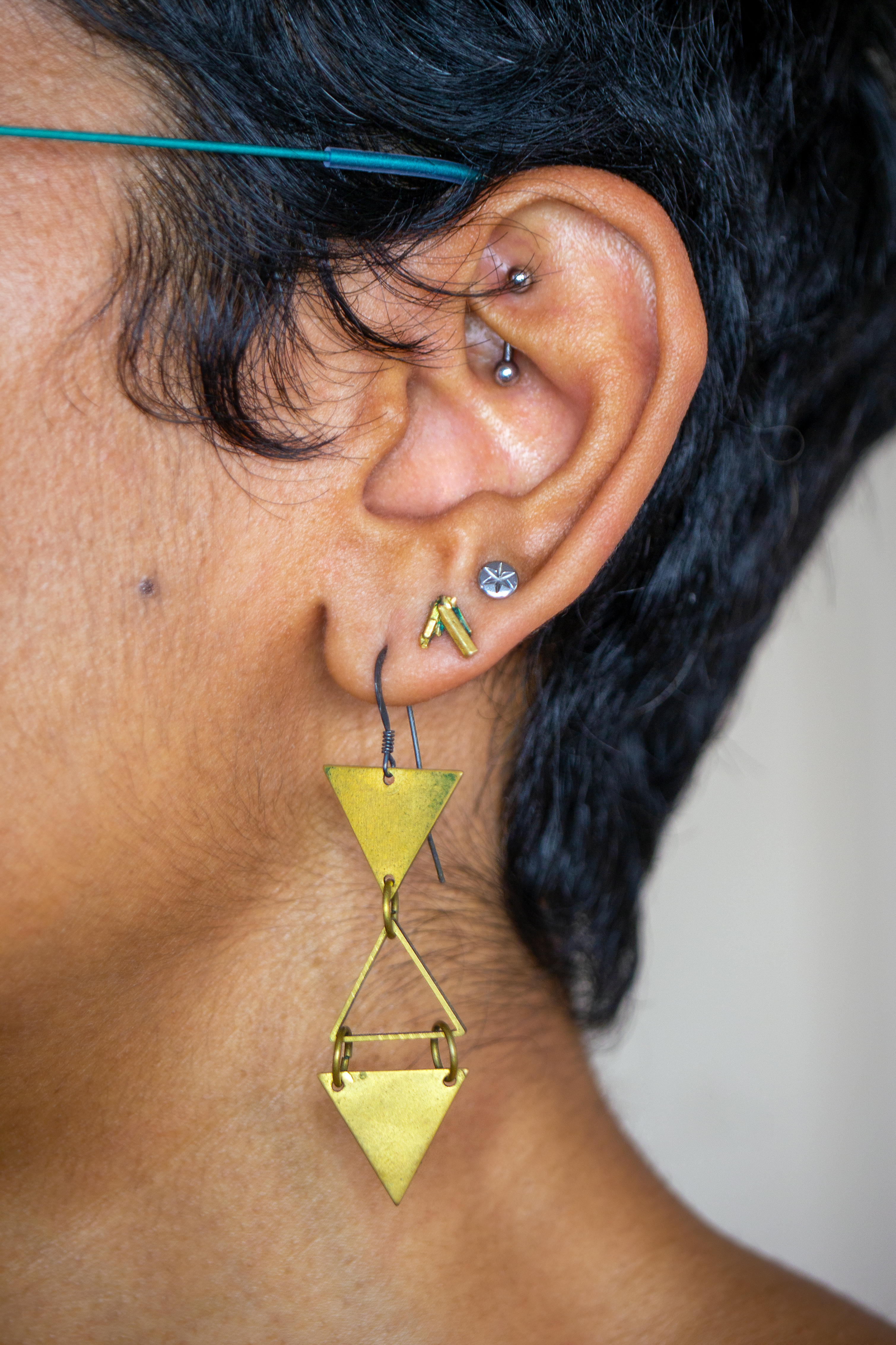 A brown ear with rook and lobe piercings.