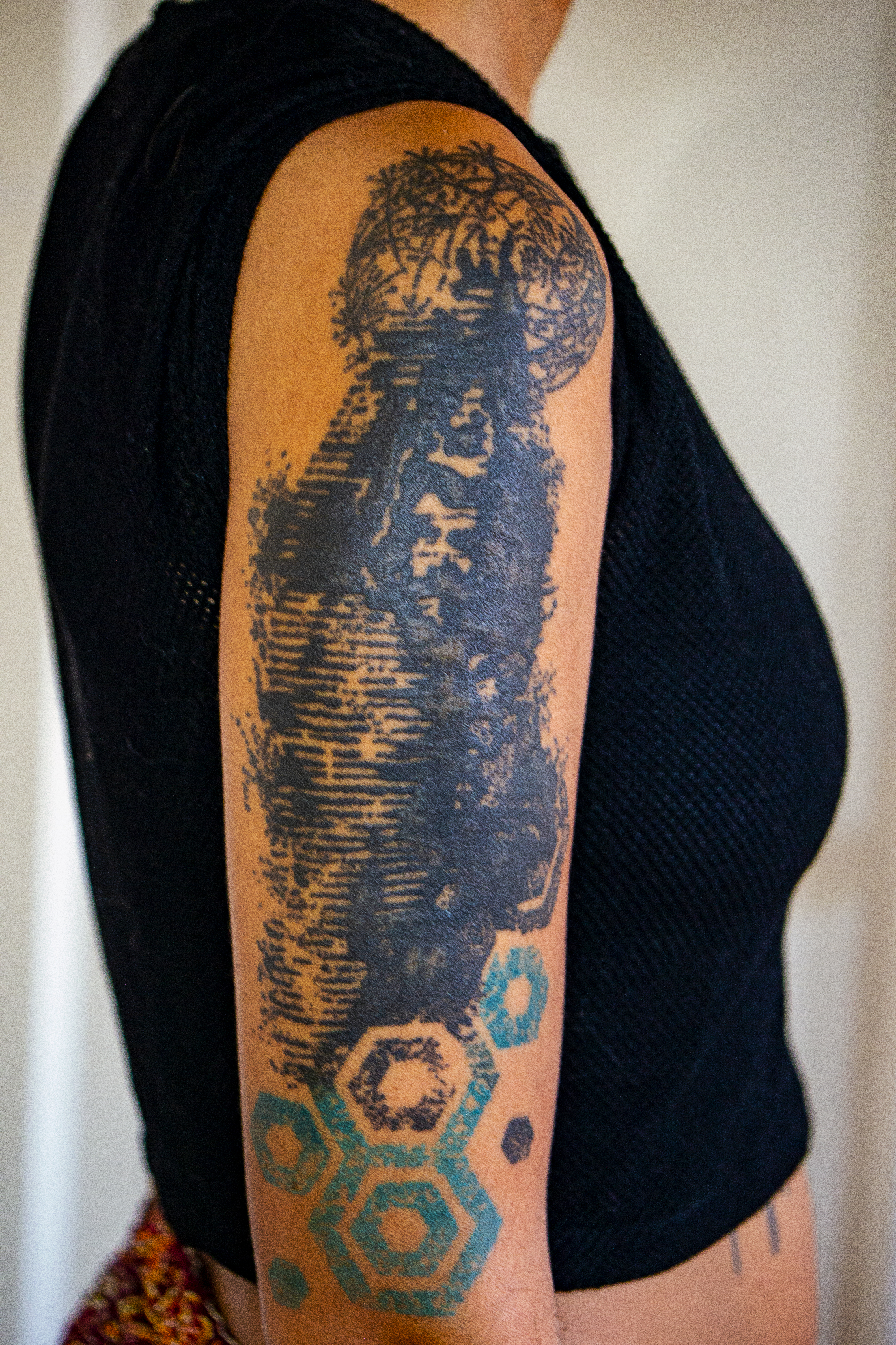 Black and blue trash polka tattoo on brown skin of Sisyphus and the rhizome.