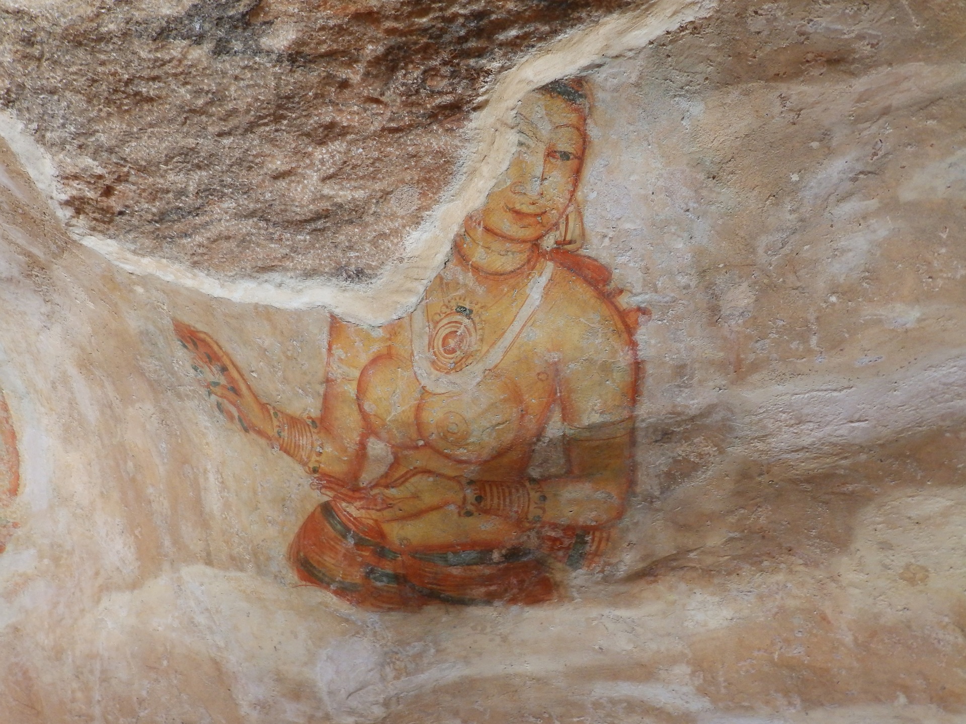 A smiling, bare-breasted Apsara painted on Sigiriya's rock wall.