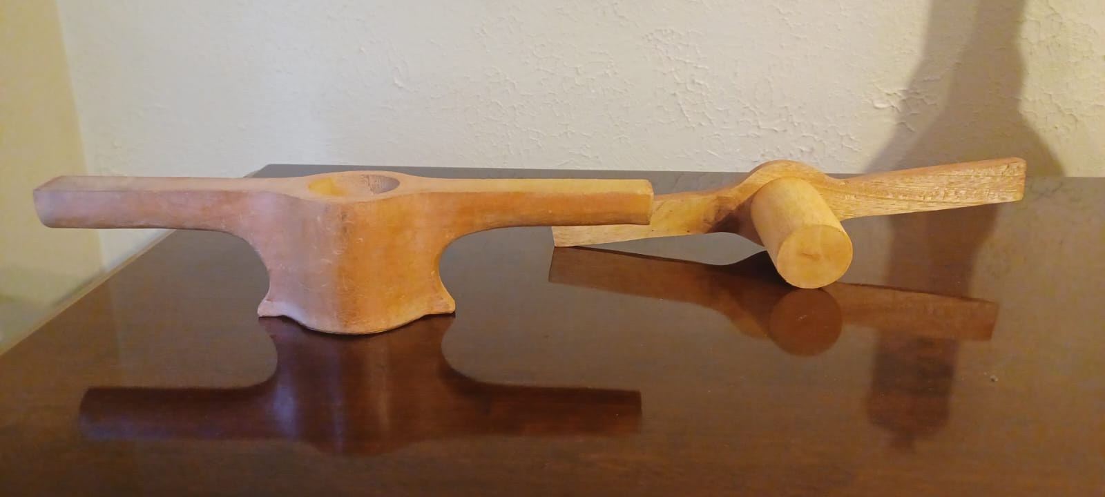 A traditional wooden stringhopper press sits on a cherry veneer table.