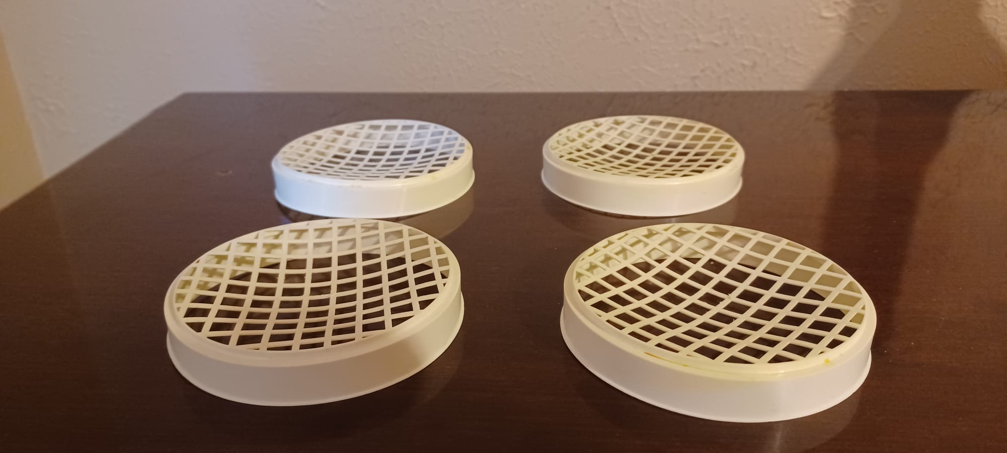 Four white, slightly convex, plastic mold mats onto which the formed idiyappam are squeezed.