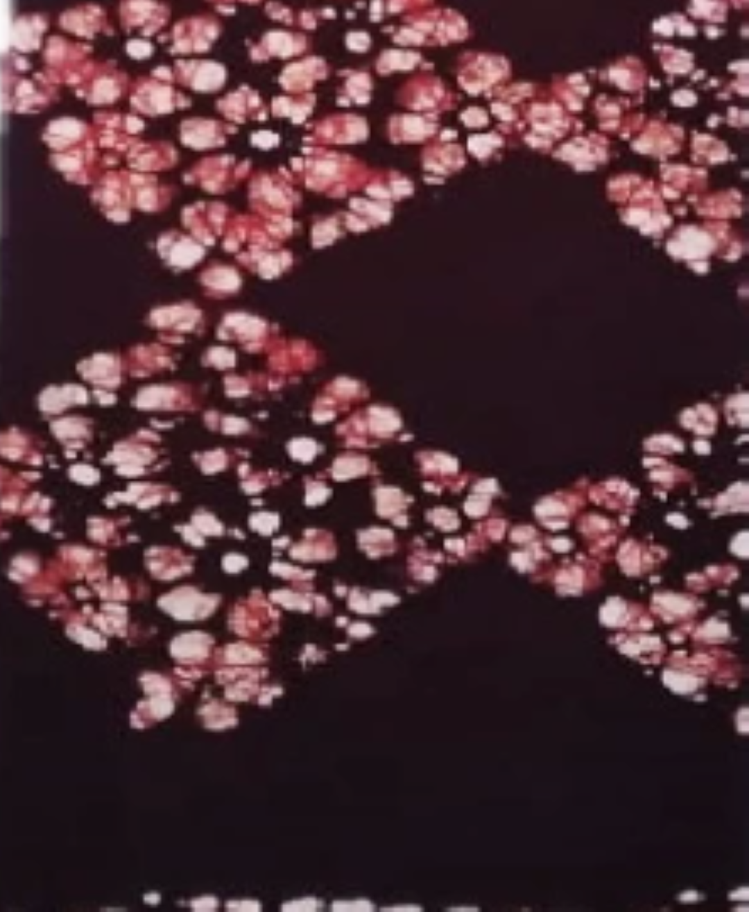 A maroon sarong with batik dots set close together to form interconnecting diamond shapes.